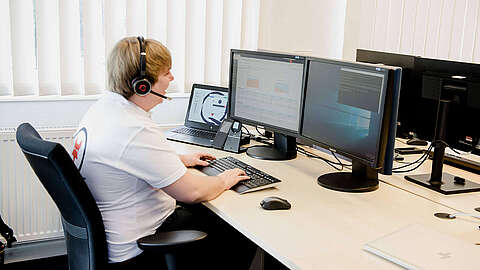Customer Service Desk MODOX-Supportmitarbeiter sitzt an einem Pc und telefoniert mit Headset